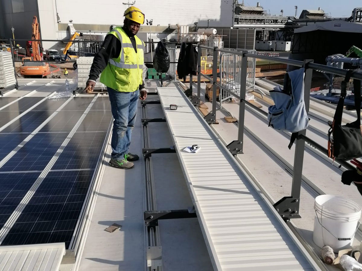 Operatore in alta visibilità su una passerella di servizio installata su una copertura industriale