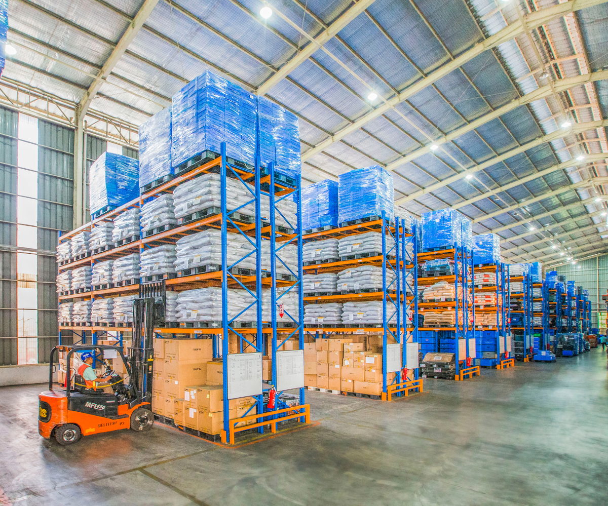 Magazzino con scaffalature, pallet accatastati e un muletto in movimento
